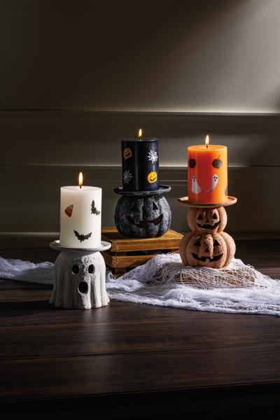 Halloween-themed candles on decorative stands with a dark background