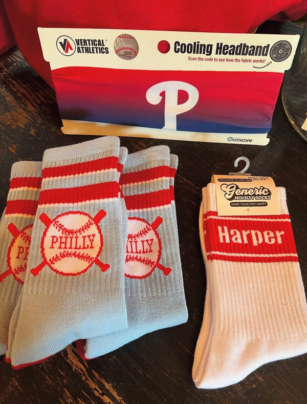 Pair of 'Philly' socks with a 'Harper' sock on a wooden surface, with a branded headband in the background.