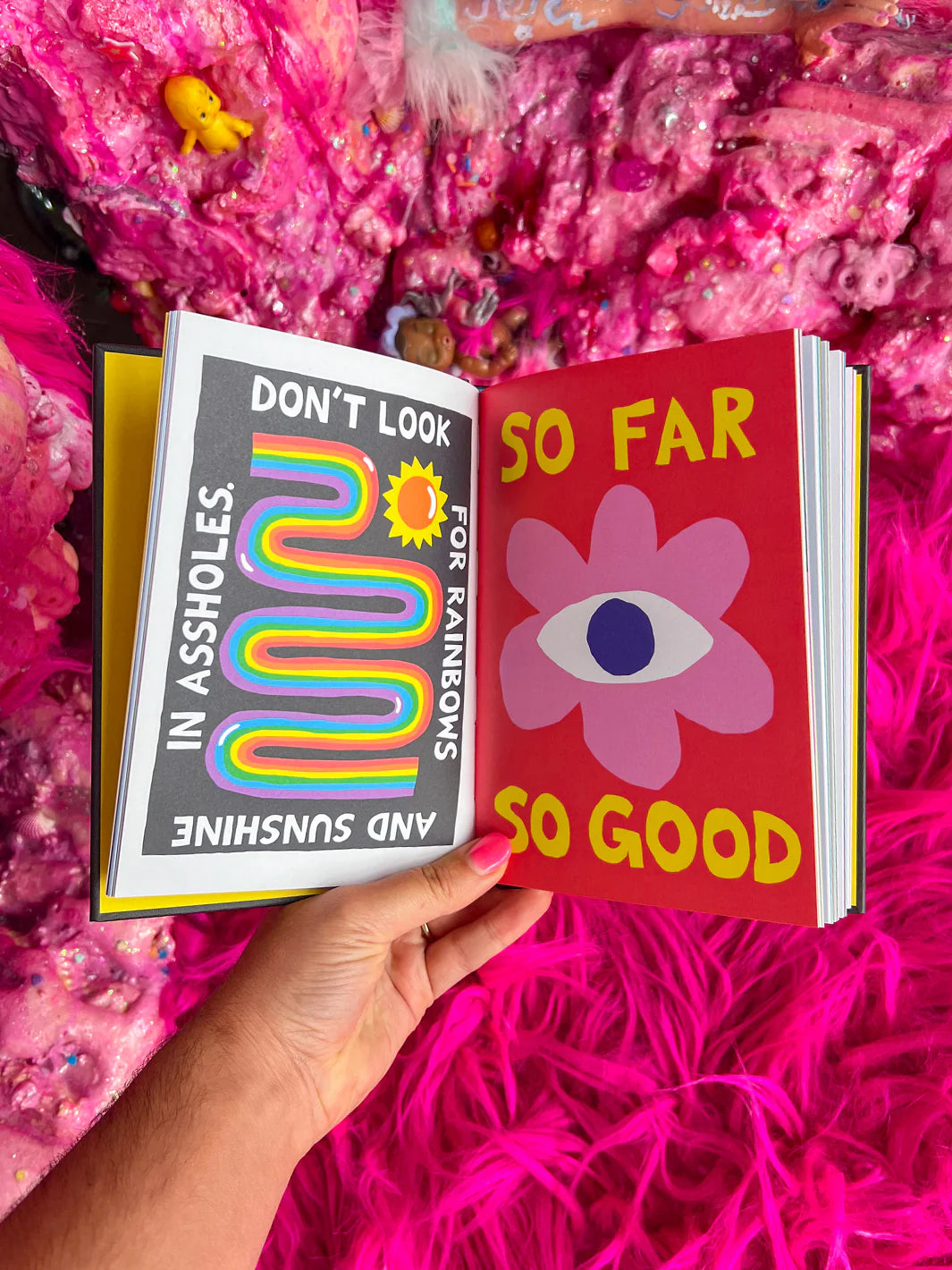 Book titled 'Don't Look for Rainbows and Sunshine' held against a pink, textured background.