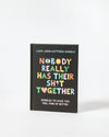 Book titled 'Nobody Really Has Their Sh*t Together' with colorful text on a black background