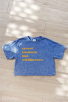 Blue t-shirt with yellow text on a wooden floor