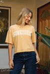 Woman wearing a 'SUNKISSED' t-shirt standing in front of a door.