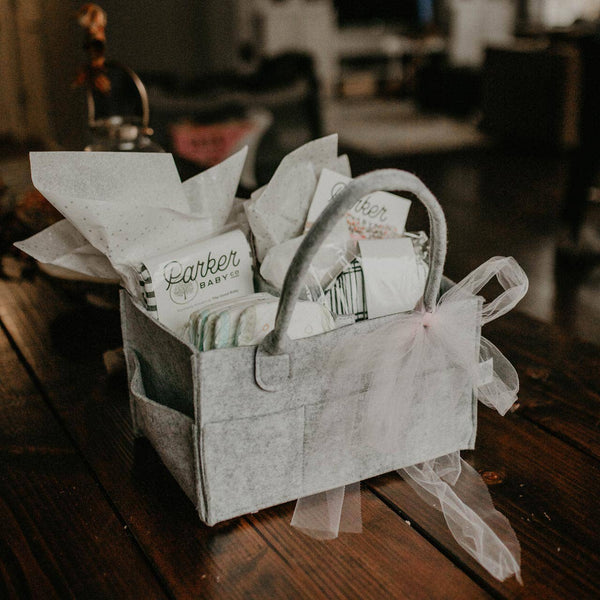 Gray gift basket with baby items on a wooden table