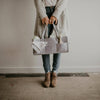 Person holding a gray patchwork bag against a plain background
