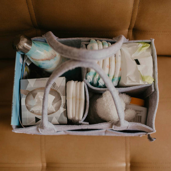 Organized toiletries in a gray fabric holder on a brown leather surface