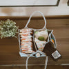 Fabric storage bag with compartments containing baby items on a wooden surface.