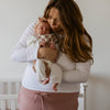 Woman holding a baby in a room with a crib in the background
