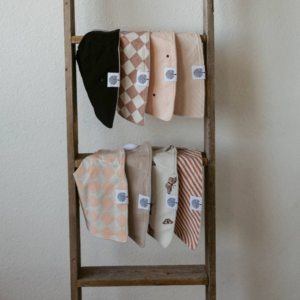 Wooden ladder with folded fabric items on a plain wall
