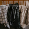 Three pieces of fabric hanging on a rack with a wooden background