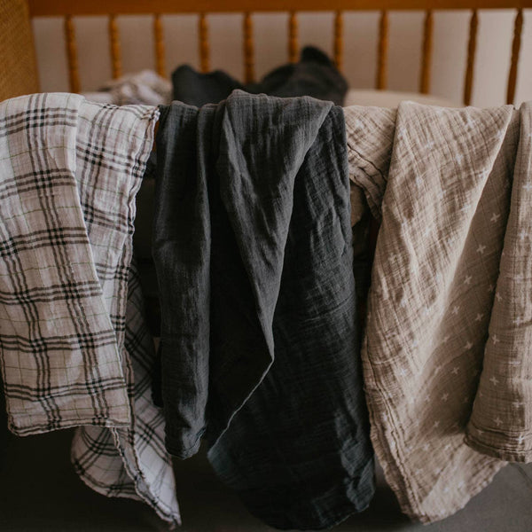 Three pieces of fabric hanging on a rack with a wooden background