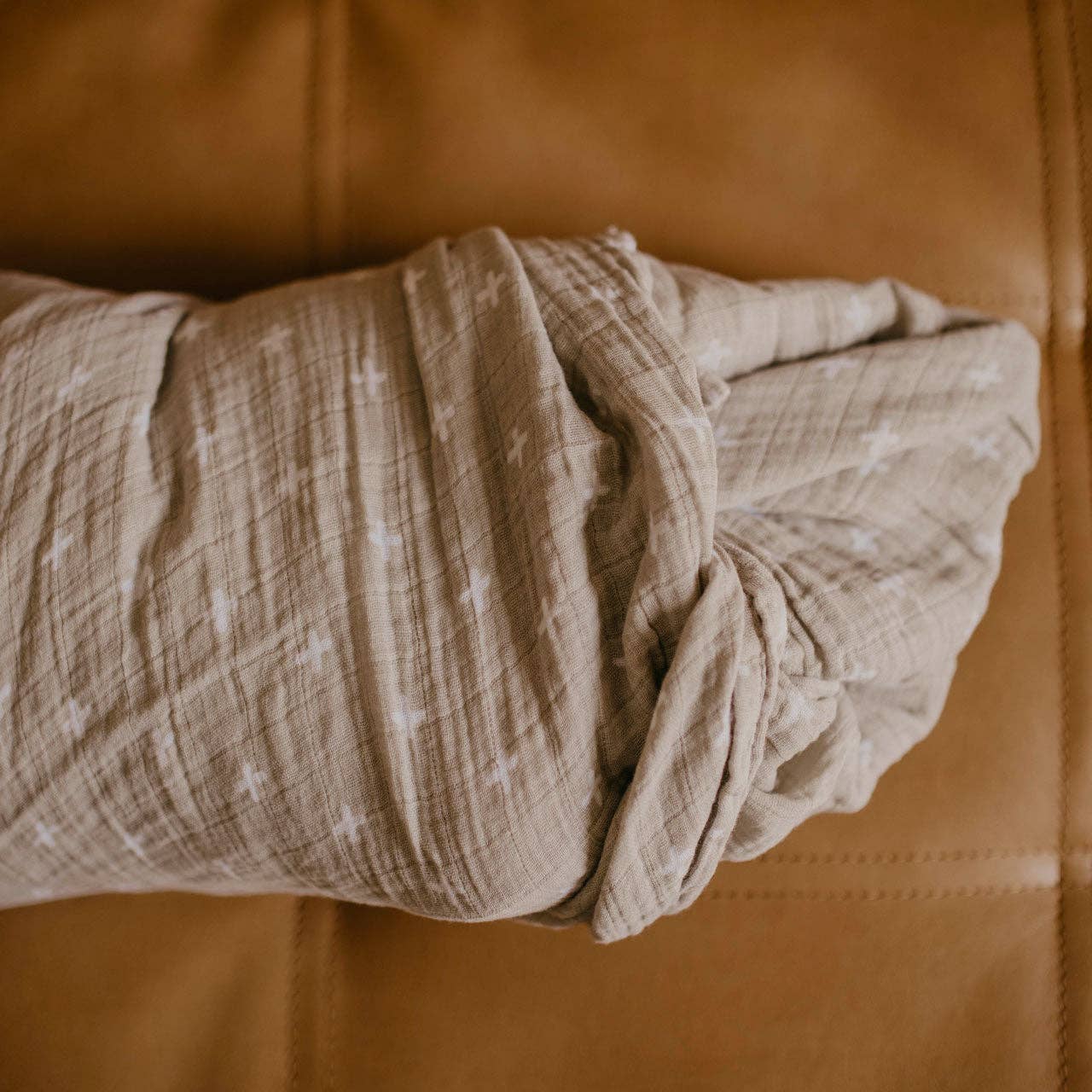 Folded beige fabric on a brown leather surface