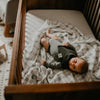 Baby lying on a plaid blanket in a crib