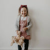 Child holding a teddy bear against a plain background