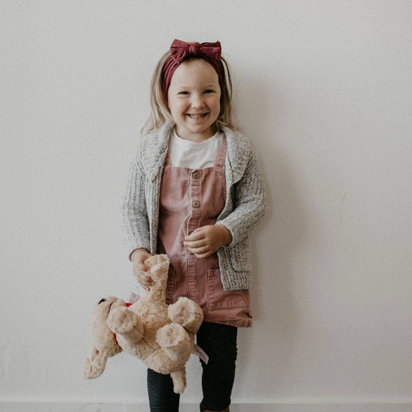 Child holding a teddy bear against a plain background