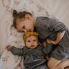 Two young children in matching outfits lying on a floral blanket.