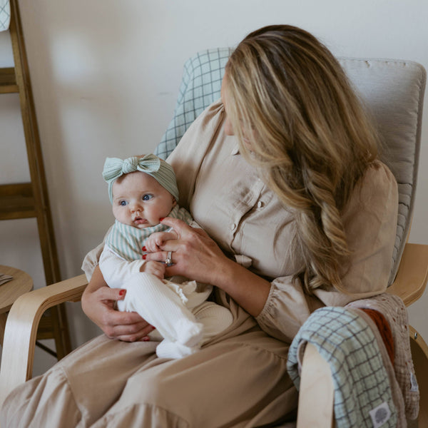 Woman holding a baby in a chair with a neutral color scheme