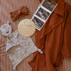 Baby items including a plush toy, headband, and ultrasound photo on a striped background