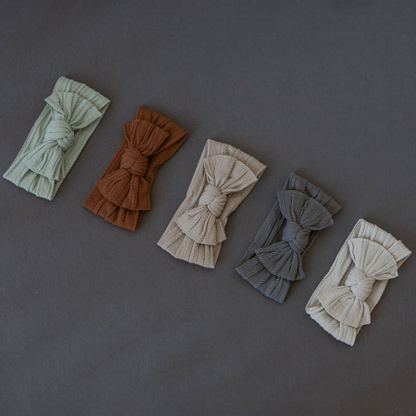 Set of five knotted headbands in various colors on a dark gray background