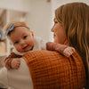 Woman holding a baby with a blue bow in a warm indoor setting