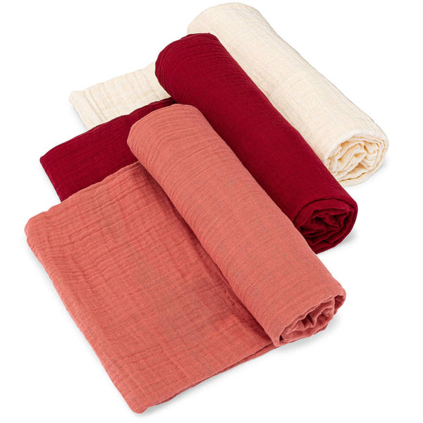 Three rolled-up fabric swaddles in red, terracotta, and cream on a white background