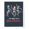 Greeting card with dancing skeletons wearing Santa hats and the text 'WE WISH YOU A Scary Christmas'