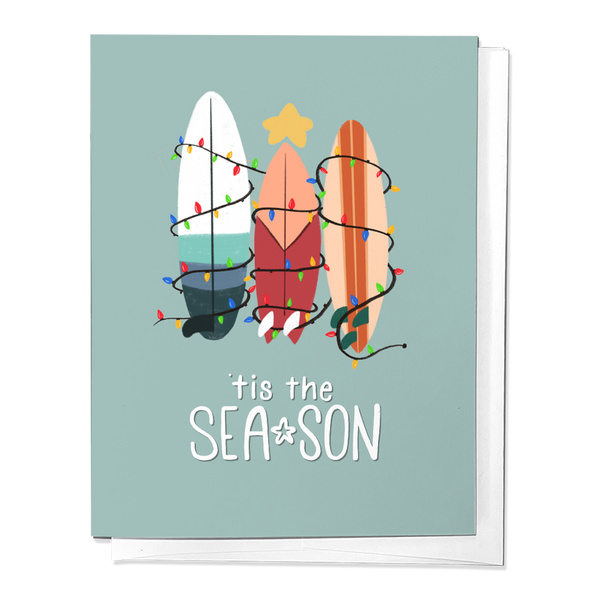 A greeting card with surfboards decorated in Christmas lights, titled 'TIS THE SEA-SON' on a blue background.