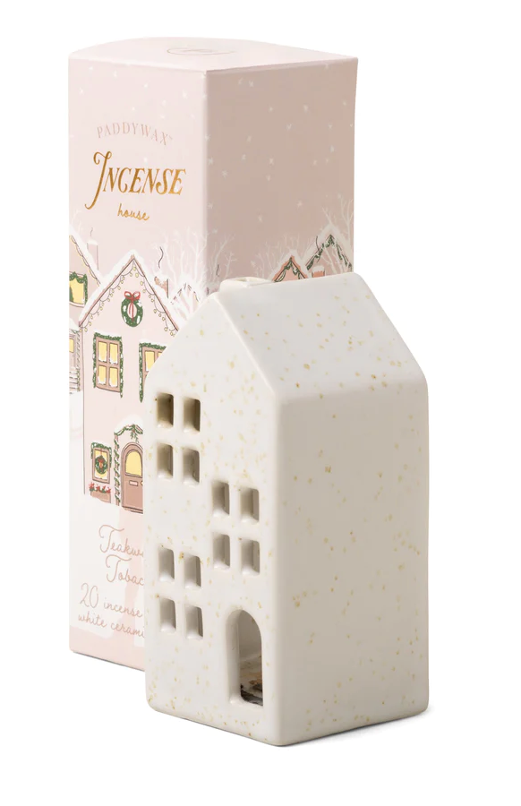 A beige ceramic incense cone holder shaped like a house, with 'Holiday Town' and 'Incense House' text on the top, next to its pink packaging box decorated with Christmas motifs.