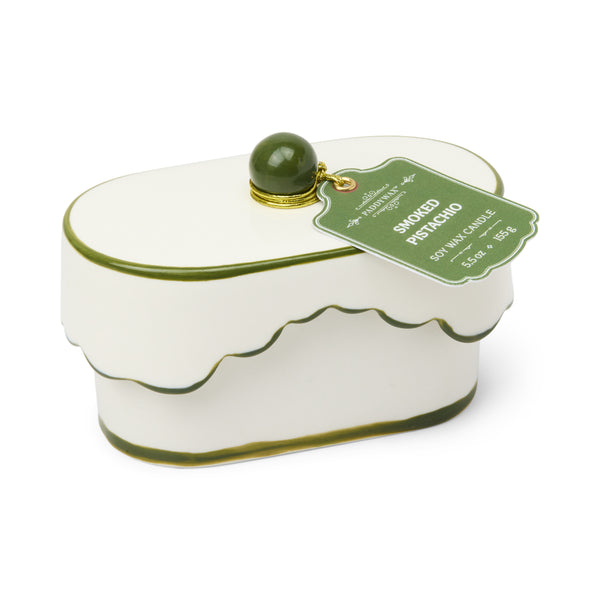 White candle container with green lid and label on a white background
