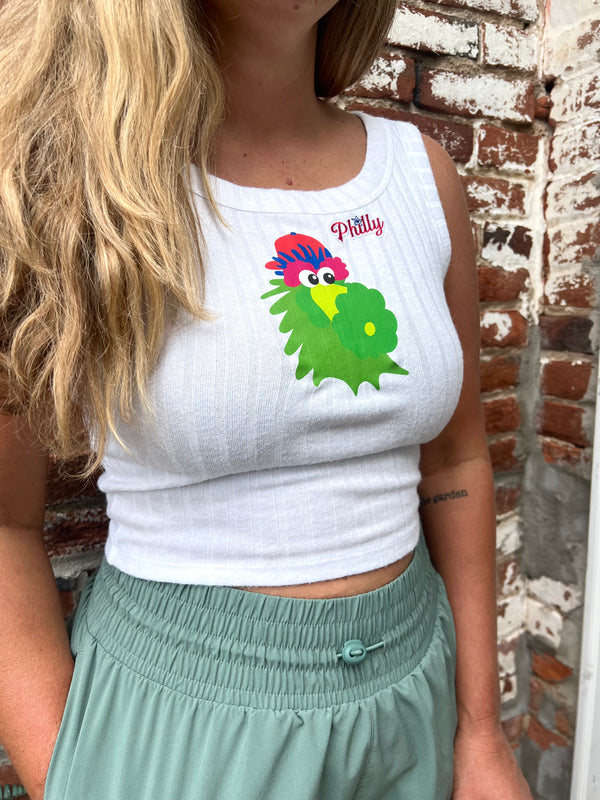 Person wearing a white tank top with a colorful Phanatic graphic against a brick wall.