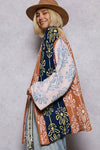 Person wearing a colorful patterned poncho against a plain background