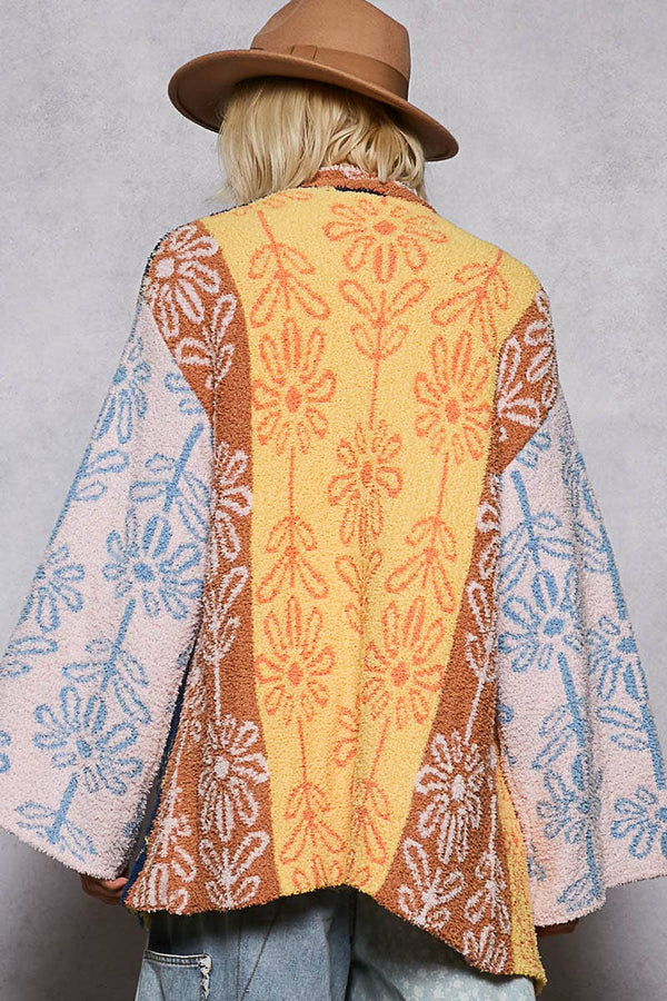 Person wearing a patterned cardigan with a plain background
