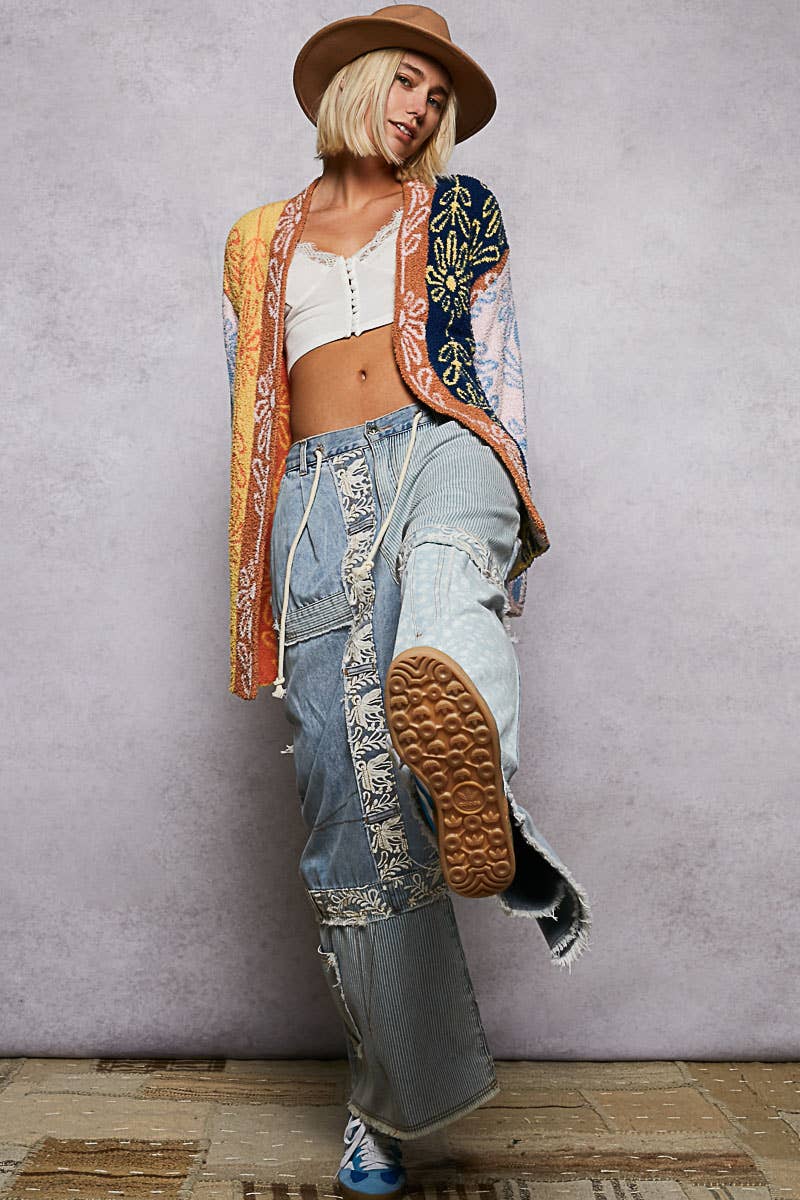 Person wearing a colorful outfit with a hat, jacket, and jeans against a plain background