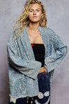 Woman wearing a patterned denim jacket over a black top against a gray background