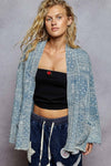 Woman wearing a patterned denim jacket over a black top with a red heart on a gray background