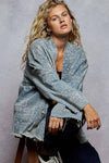 Woman wearing a blue patterned kimono-style jacket against a gray background