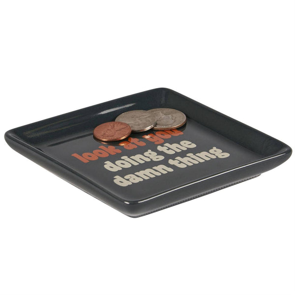 Black tray with coins and humorous text on a white background