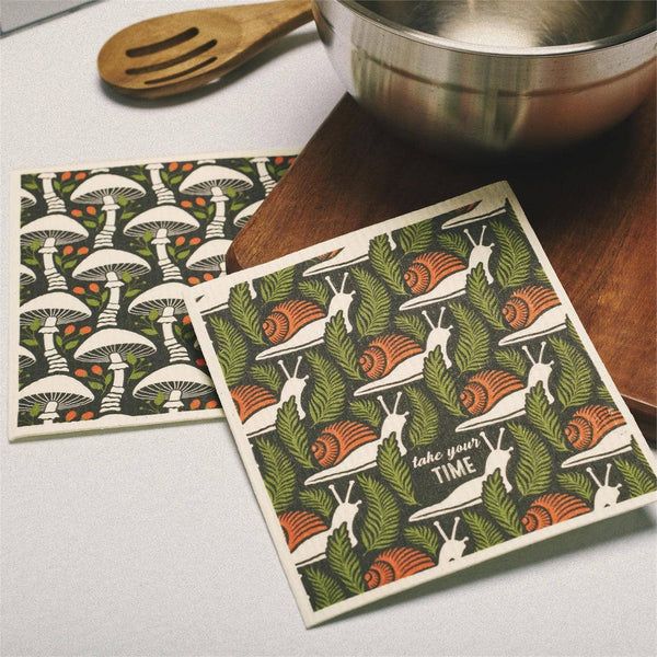 Two patterned coasters on a kitchen counter with a wooden spoon and metal bowl.