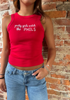 Person wearing a red tank top with text, standing against a brick wall.