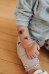 Child's arm with bee tattoos on a wooden floor background