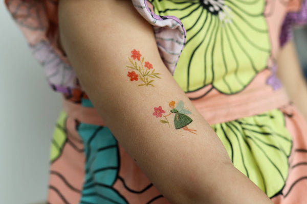 Temporary tattoo of a woman and flowers on a person's arm.