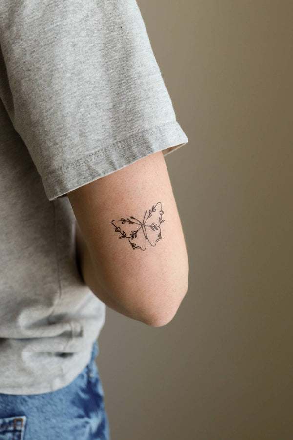 A person's forearm with a temporary tattoo of two butterflies