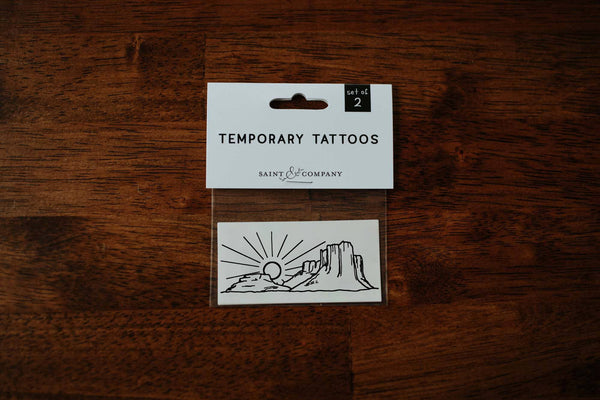 A set of temporary tattoos featuring a hand-drawn desert scene, packaged on a card.