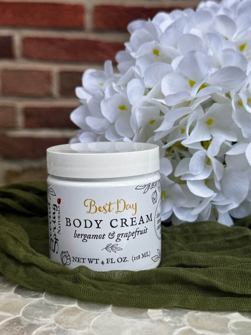 Jar of body cream with flowers and green fabric in the background