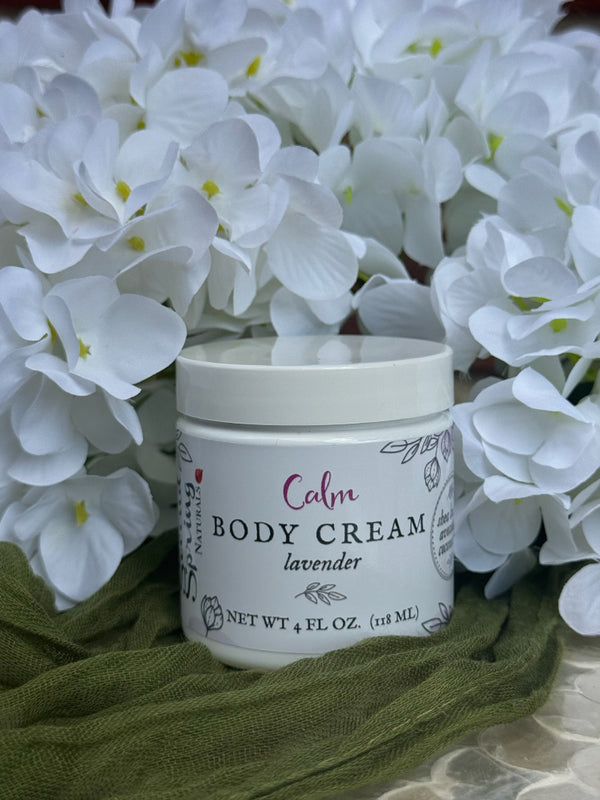 Jar of body cream labeled 'Calm' with lavender scent, surrounded by white flowers.