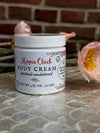 Jar of Hippie Chick body cream on a stone surface with flowers in the background