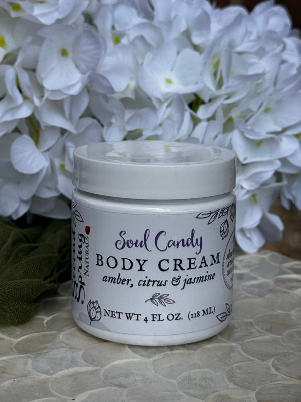 Jar of Soul Candy body cream with white flowers in the background