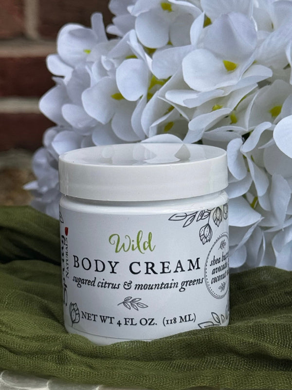 Jar of Wild Body Cream with white flowers in the background