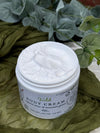 Jar of Wild Body Cream on a green fabric background with plants.