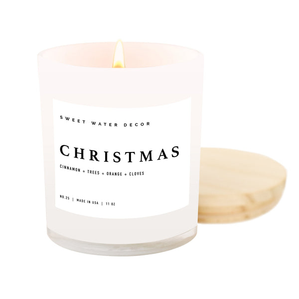 An 11 oz soy wax candle with a white label that reads 'Christmas', placed in a white jar with a wooden lid, on a white background.