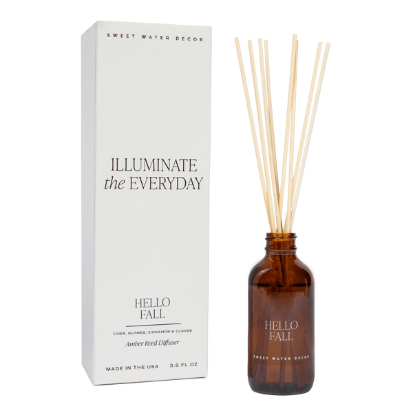 A brown glass reed diffuser bottle with 'Hello Fall' branding, alongside a white box packaging with the text 'Illuminate the Everyday'.